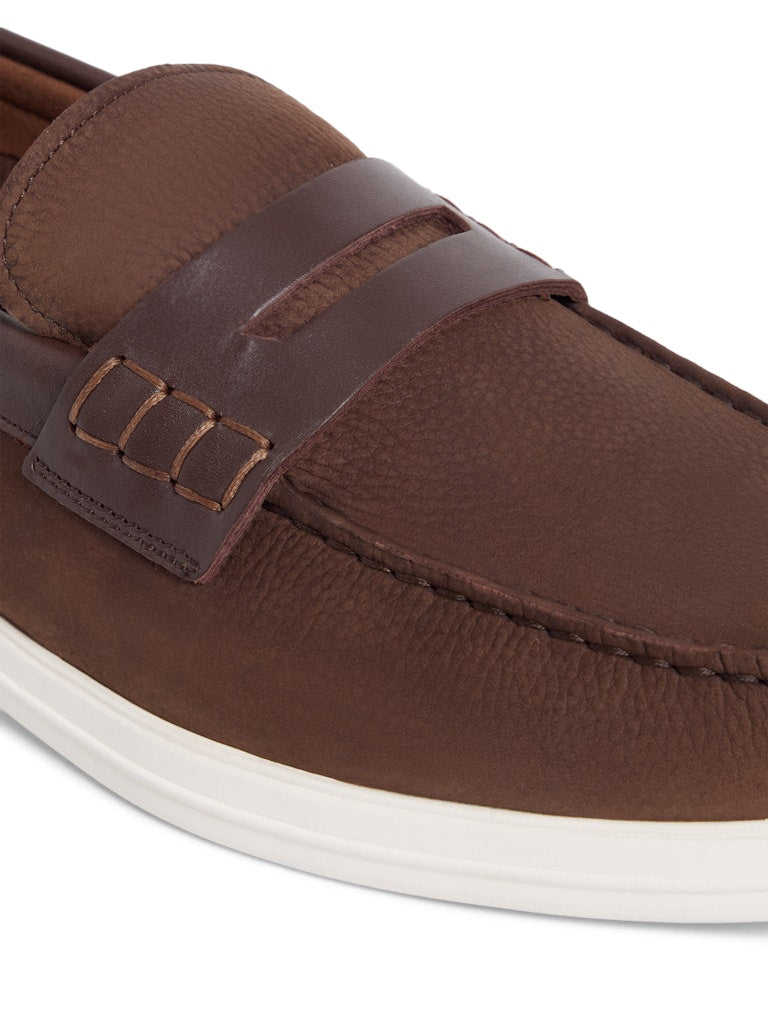 Close up of brown leather loafers with white sole and leather penny strap