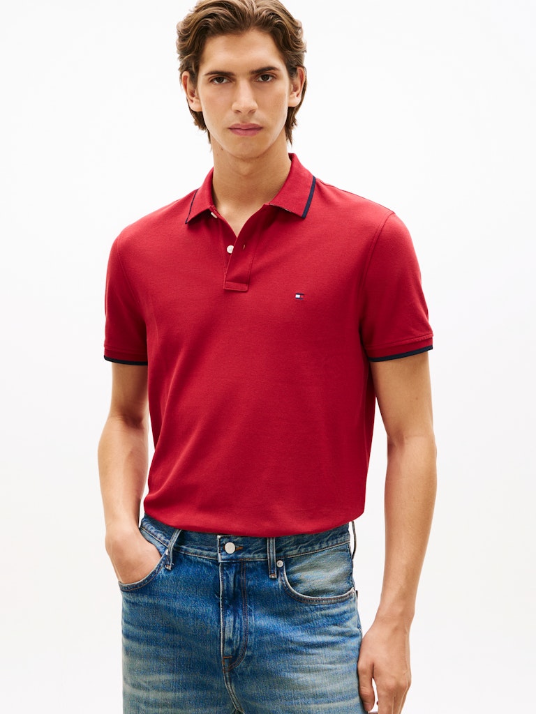 Man wearing a red polo shirt with navy trim on a white background
