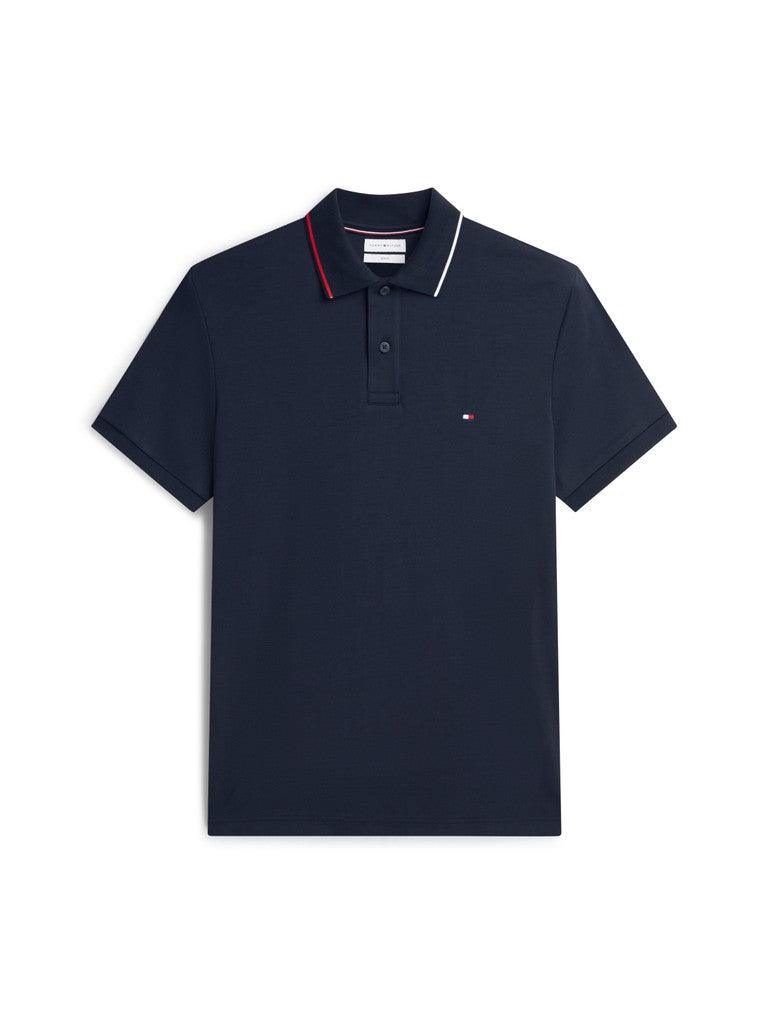 A navy blue short-sleeve polo shirt with a classic collar featuring white and red stripe detailing, and a small embroidered Tommy Hilfiger flag logo on the left chest, displayed on a clean white background.