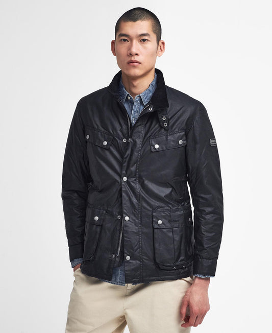 Barbour International Tourer Duke Wax Jacket. Man wearing a black jacket with a light shirt and beige pants on a white background - Matt O'Brien Fashions