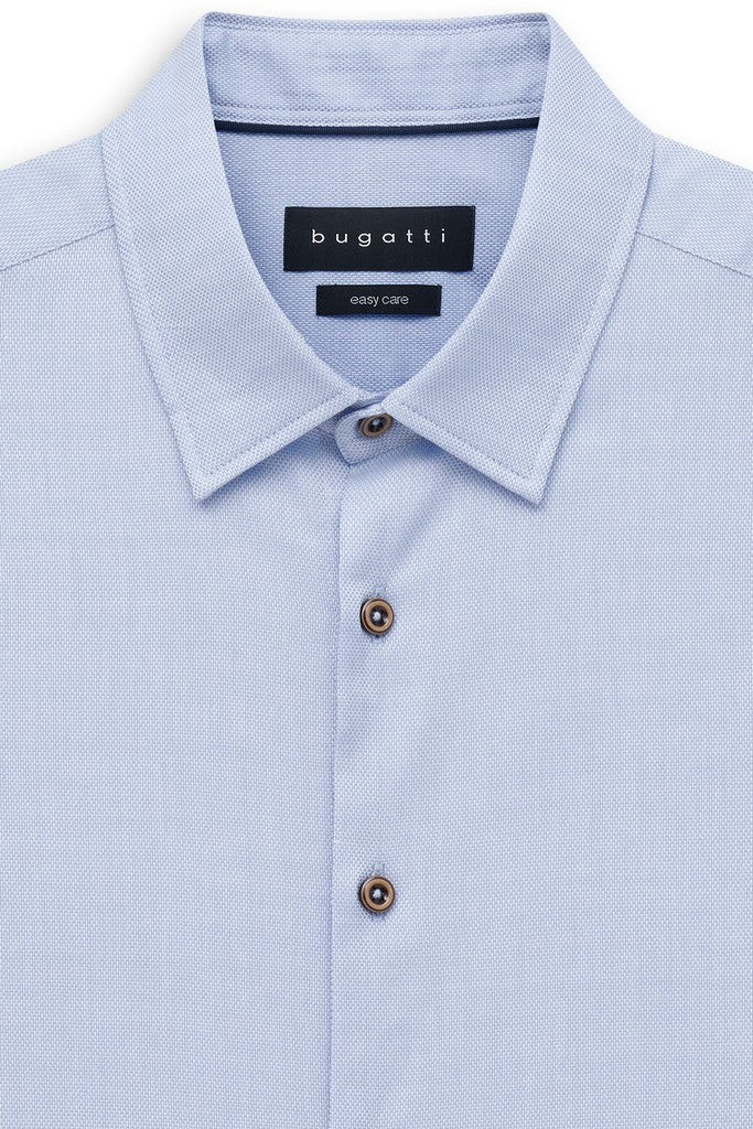 Close-up of a light blue Bugatti shirt with a subtle micro-pattern, featuring a classic collar, button-down front, and dark brown buttons.