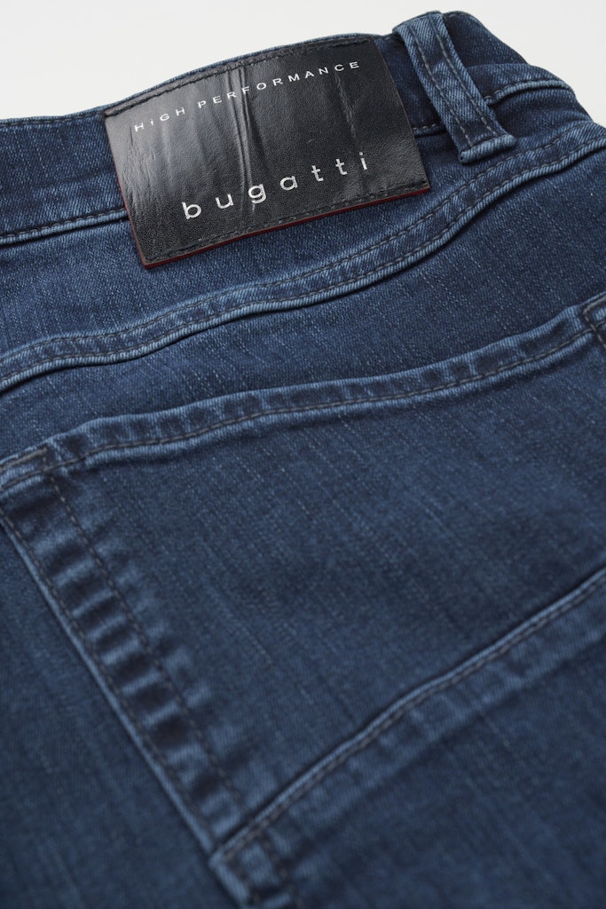 Close-up of dark blue denim jeans showing the back pocket and waistband with a black Bugatti brand patch.