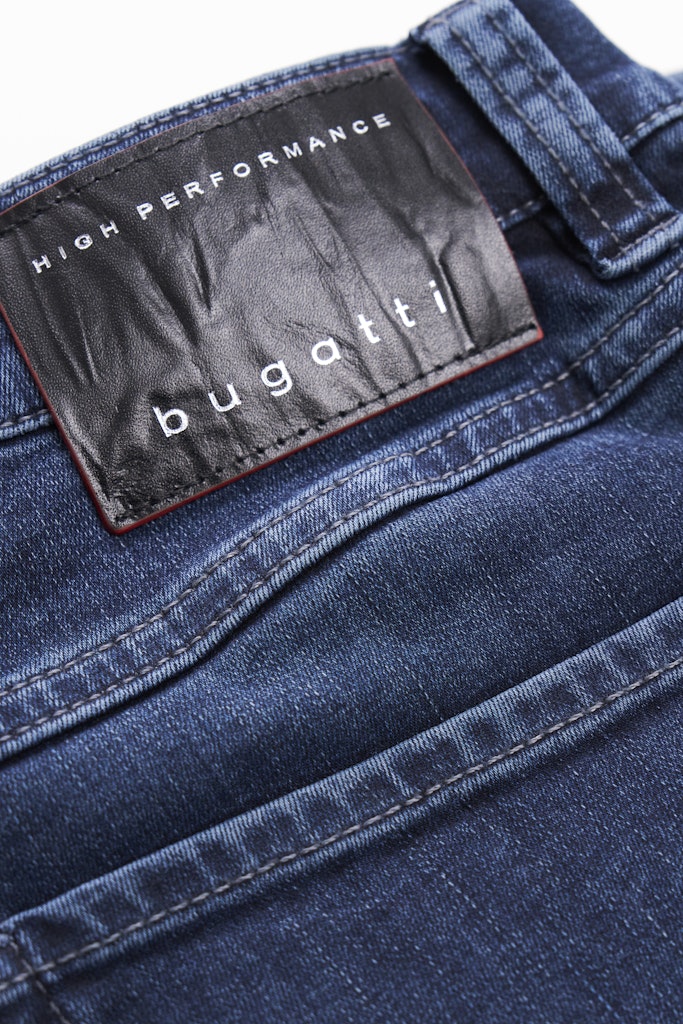 Close-up of the waistband of blue denim jeans featuring a black Bugatti leather patch with white text that reads 'HIGH PERFORMANCE bugatti'.