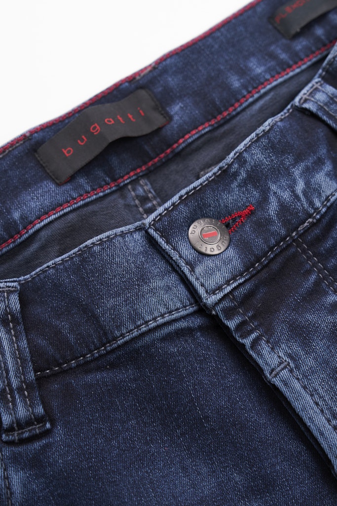 Close-up of dark blue denim jeans showing the waistband, button closure, and red contrast stitching. A black brand label reading bugatti is visible inside the waistband.