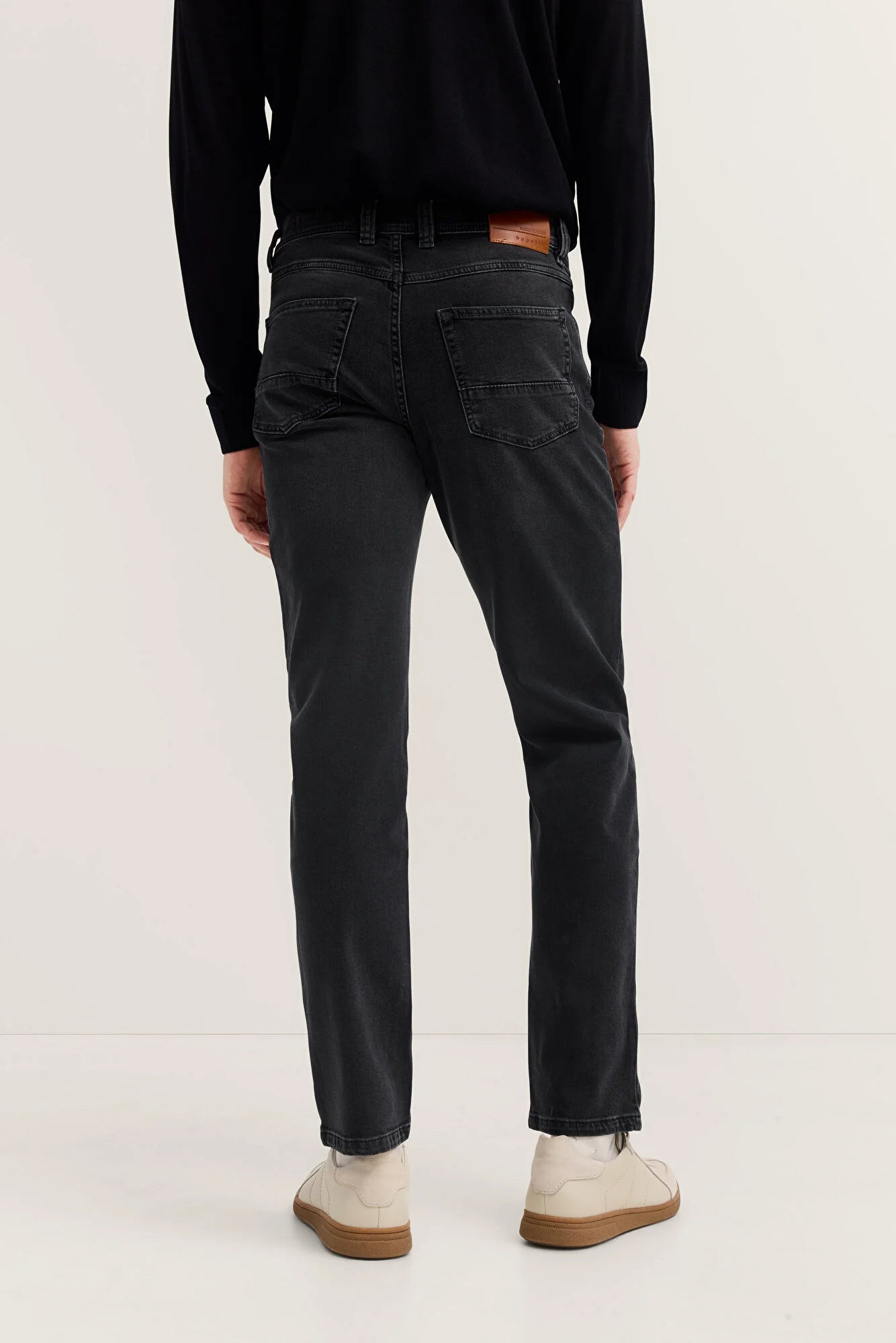 Person wearing black jeans and a black top on a white background